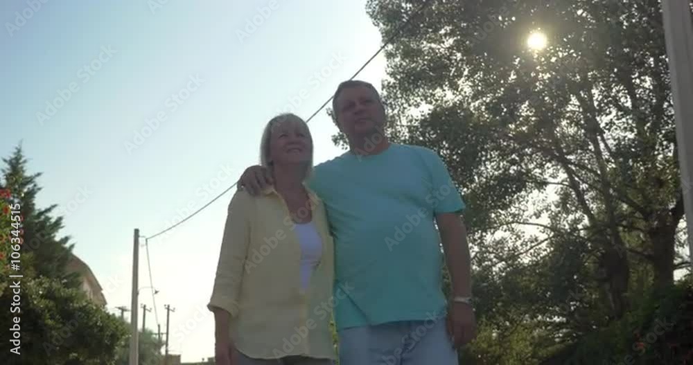 Steadicam shot of happy mature couple walking in country town in sunny day holding hands. Steadicam shot of happy mature couple walking in country town in sunny day holding hands.