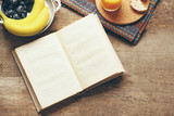 Open book and snack on wooden table background