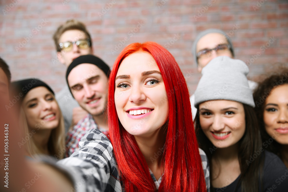 Young people taking group photo on brick wall background Young people taking group photo on brick wall background