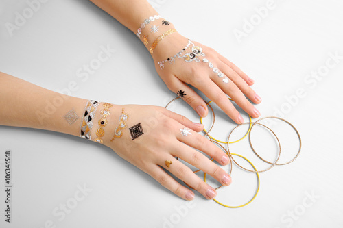 Female hands with flash tattoo holding bracelets on white background