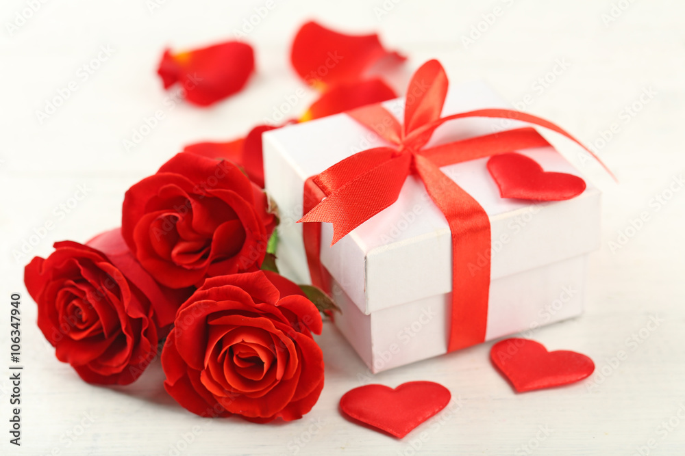 Gift box, rose flowers and decorative hearts on light wooden background Gift box, rose flowers and decorative hearts on light wooden background