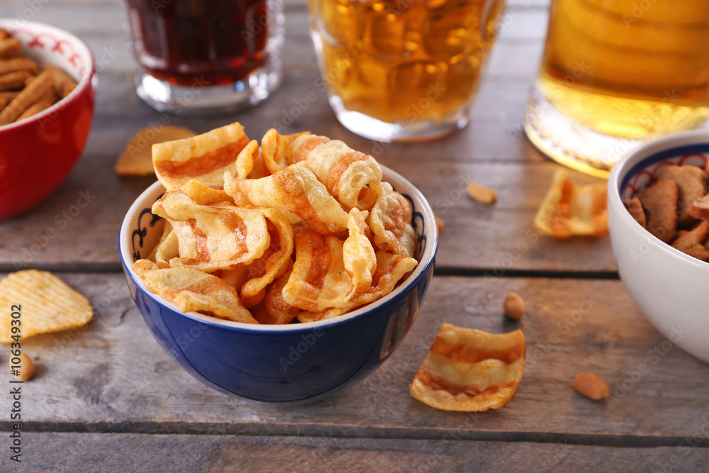 Mugs of beer and bowls with snacks on wooden table Mugs of beer and bowls with snacks on wooden table