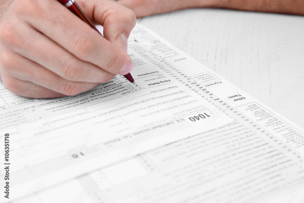 Man filling American form of Individual Income Tax Return at the table Man filling American form of Individual Income Tax Return at the table
