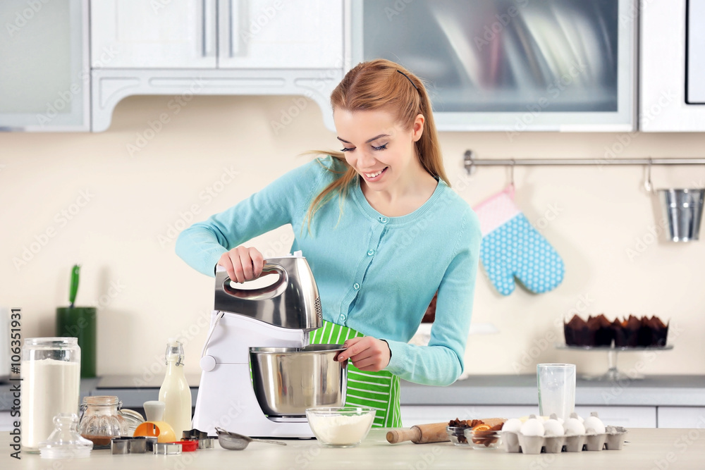 Young woman using a food processor to make a dough Young woman using a food processor to make a dough