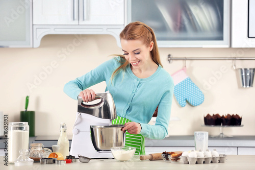Obraz na plátně Young woman using a food processor to make a dough