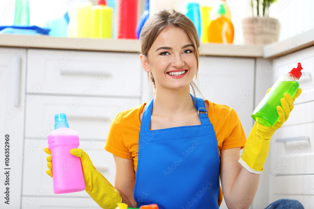 Cleaning concept. Young woman sitting on the floor with cleaning fluids Cleaning concept. Young woman sitting on the floor with cleaning fluids