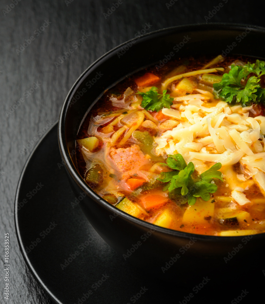 Minestrone -italian soup with vegetables. Black bowl on black board. Minestrone -italian soup with vegetables. Black bowl on black board.