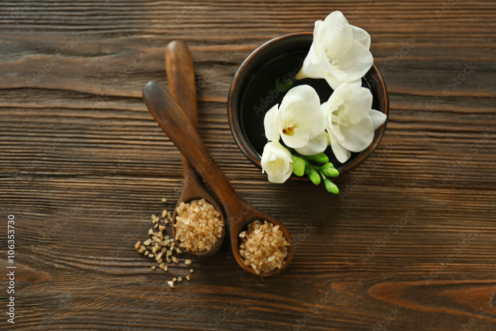 Wooden spoons with sea salt and exotic flower on wooden background Wooden spoons with sea salt and exotic flower on wooden background