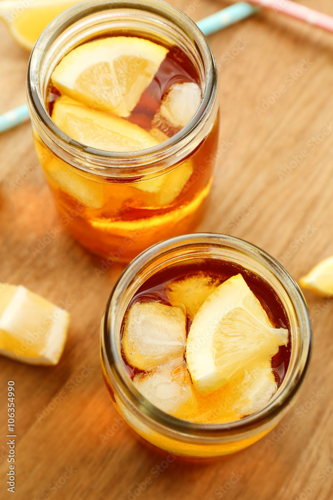 Jar of ice lemon tea with straw on wooden table Jar of ice lemon tea with straw on wooden table