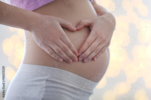 Wallpaper Mural Pregnant woman making heart with her hands on blurred glitter background Torontodigital.ca