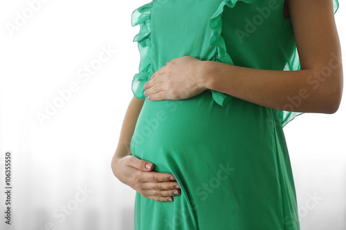 Pregnant woman in green dress near window