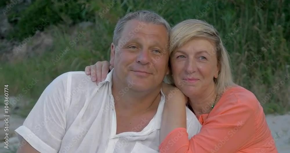 Loving mature couple outdoor. They looking into distance close to other, woman embracing mans over shoulders. Always together Loving mature couple outdoor. They looking into distance close to other, woman embracing mans over shoulders. Always together