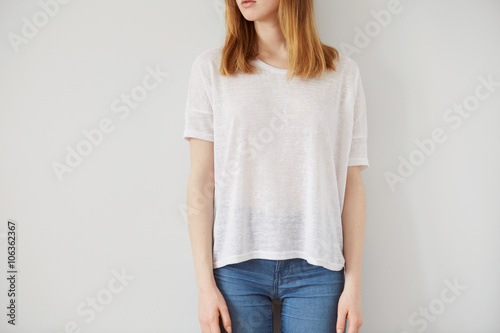 Young girl wearing blank wthite t-shirt. Wall background. photo