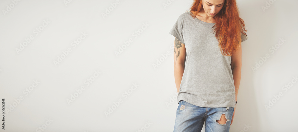 Young girl wearing grey blank t-shirt and blue jeans. Concrete wall
