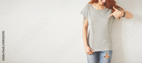 Young girl wearing grey blank t-shirt and blue jeans. Concrete wall background with copy space for your text message or promotional content