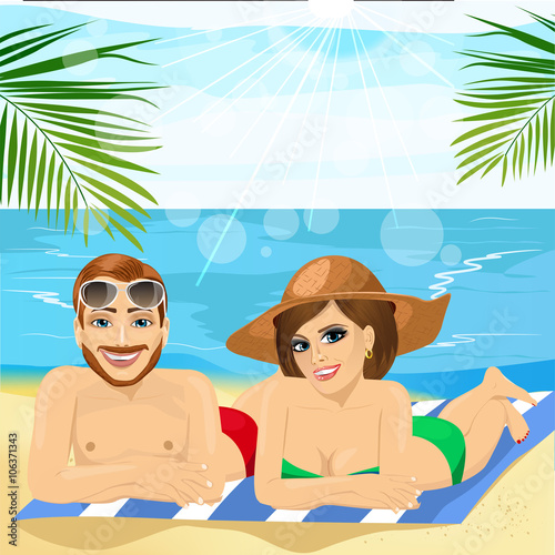 romantic couple wearing swimsuit lying together on towel at the beach