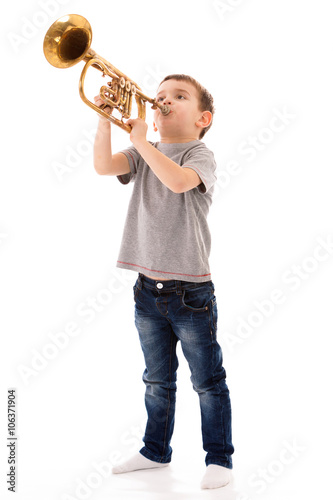 young boy blowing into a trumpet against white background