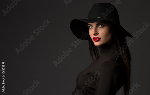 Fashion portrait of young beautiful woman model in casual wear. Black boots, hat and black dress. Copy space. 
