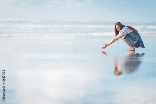 Young pretty stylish woman posing at amazing New Zealand beach with blue ocean, enjoy her vacation and summer sunny day
