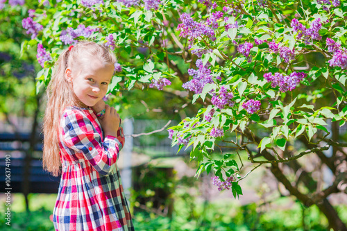 Little adorable girl smelling colorful flowers outdoors