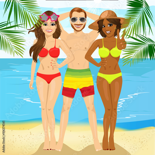 macho man standing with two attractive women on tropical beach