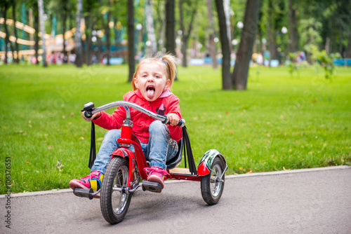 Little girl in amusement park riding on tricycle © bodich