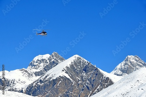 Вертолет в полете над заснеженными вершинами Гималаев