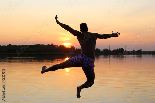 Young man jumping into lake  