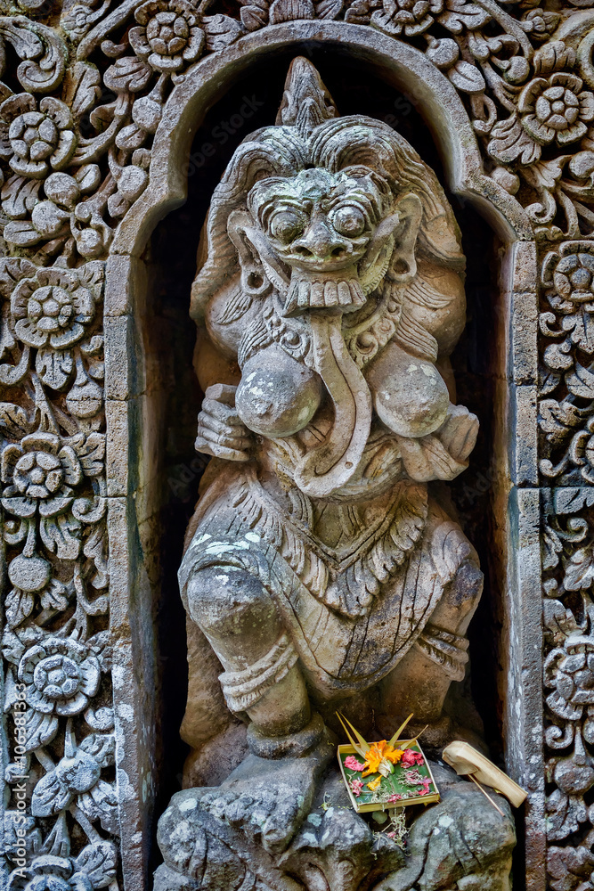 Carved stone statue of a Hindu god in an alcove with daily offering, Ubud, Bali, Indonesia