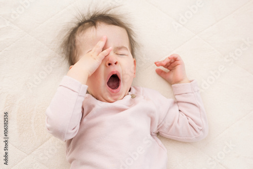 Sleeping beautiful and yawning baby toddler on the bed. Portrait