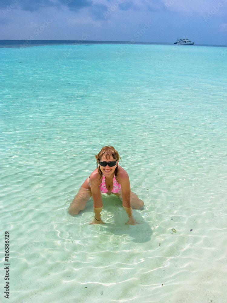 Attractive sexy woman with sunglasses and pink bikini enjoying sunny day on  crystal water. Beautiful girl sunbathing under summer sun lying in tropical  lagoon of Maldives. Atoll Asdu, Indian Ocean. Stock Photo