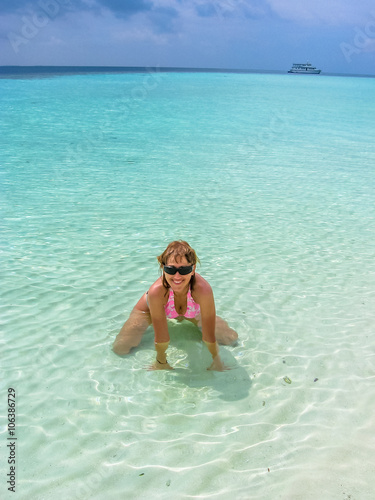 Attractive sexy woman with sunglasses and pink bikini enjoying sunny day on crystal water. Beautiful girl sunbathing under summer sun lying in tropical lagoon of Maldives. Atoll Asdu, Indian Ocean.