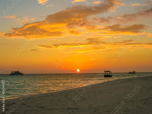 Maldives background. Sunset over the tropical sea and coral beach with colorful clouds in the sky. Boats on the horizon in heavenly atoll of peace and relaxation. North Male Atoll Asdu, Indian Ocean. © bennymarty