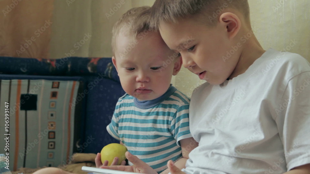 Two young white kids playing with a tablet. Two young white kids playing with a tablet.