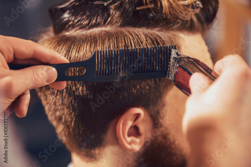 Cuadro en lienzo Peluquero profesional cortando el cabello de su cliente