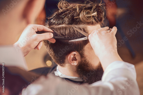 Professional barber styling hair of his client photo