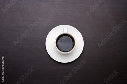 White cup of coffee on black table, top view