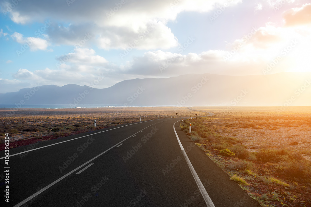 Highway on the deserted landscape on the sunset on Fuerteventura island in Spain