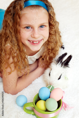 Cute little girl with a bunny rabbit has a easter at white carpe