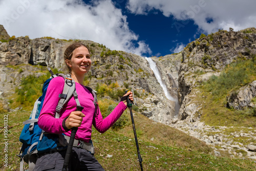 Woman trekking in Caucasus mountains against high waterfal in Us