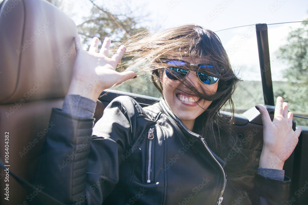 Woman with sunglasses and hands up in a convertible car Woman with sunglasses and hands up in a convertible car