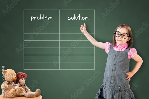 Cute little girl wearing business dress and showing problem and solution list in blank on green chalk board.