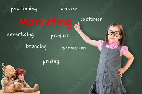 Cute little girl wearing business dress and shows on green chalk board marketing.