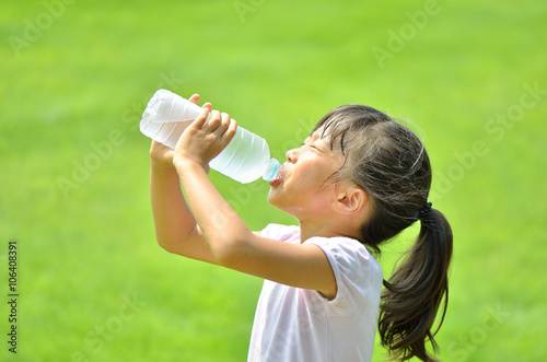 芝生広場で水を飲む女の子