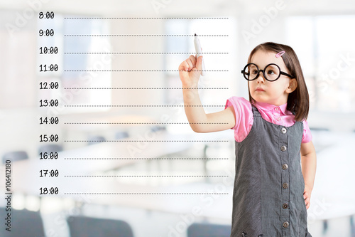 Cute little girl wearing business dress and writing blank appointment schedule. Office background.