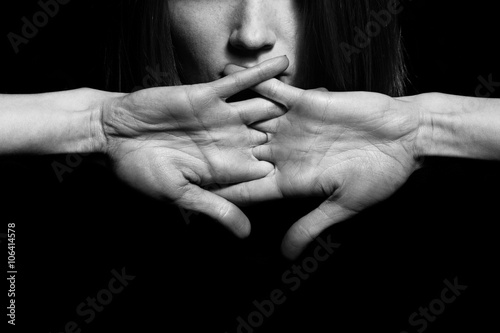 Closeup portrait of young woman hiding mouth by hands