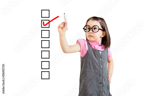 Cute little girl wearing business dress and checking on checklist box. White background.