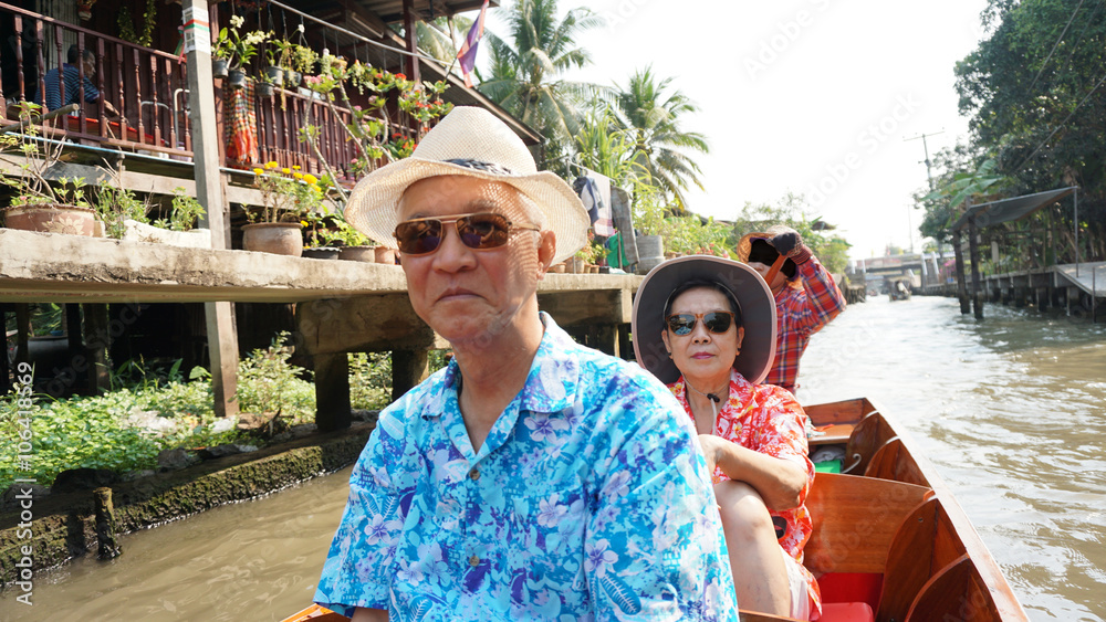 Obraz premium Chinese Asian senior couple travel to thailand cruising on the boat in floating market