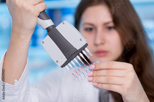 Woman technician with multipipette in genetic laboratory
