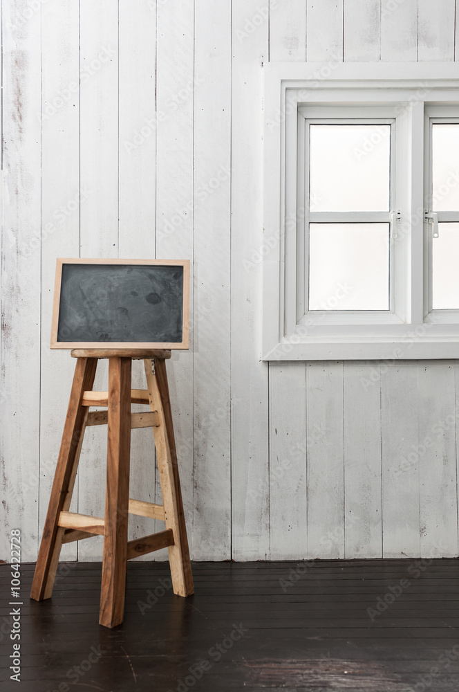 Chalkboard and round wooden chair on a dark timber wood floor, n Chalkboard and round wooden chair on a dark timber wood floor, n